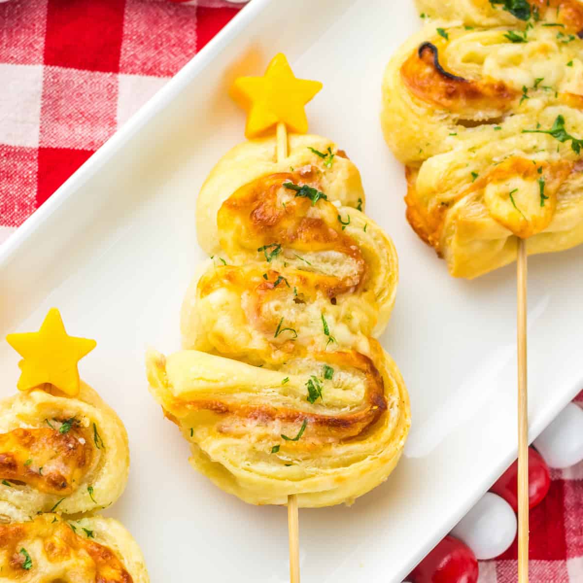 Ham and cheese puff pastry Christmas tree with crispy edges, layers of ham, melted cheese, and a parsley garnish, finished with a small cheddar star on top.