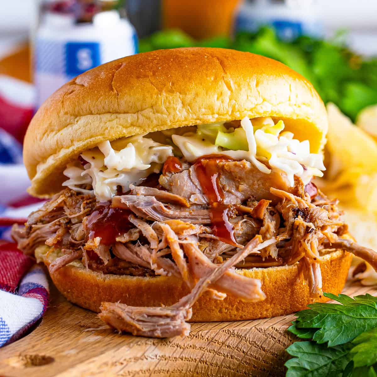 A close-up of an oven BBQ pulled pork sandwich on a soft bun, topped with creamy coleslaw and BBQ sauce.