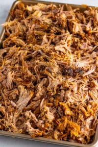 Close-up of tray of barbecue shredded pulled pork with crispy browned edges on a tray.