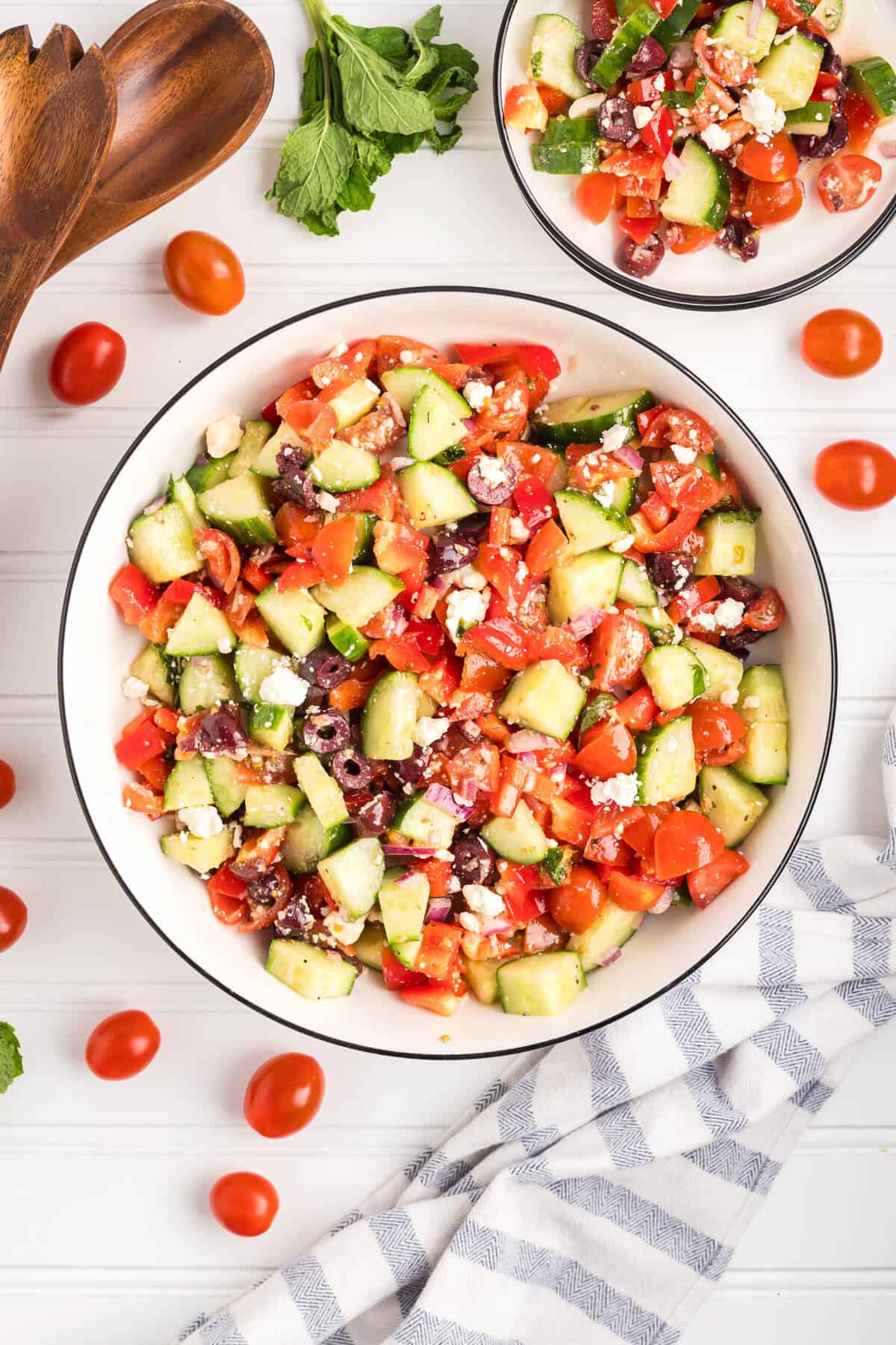 A top-down view of a large bowl of chopped Greek salad with a smaller serving bowl nearby.