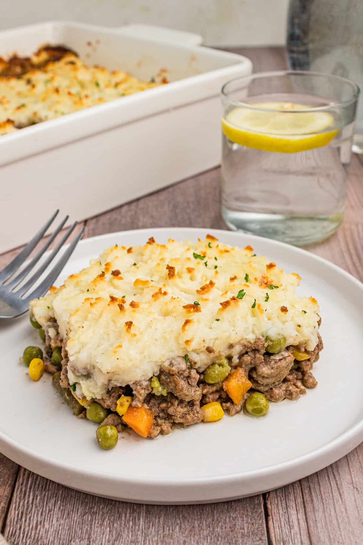 A plated slice of cottage pie on a white dish, showcasing the layered mashed potatoes and beef filling with vegetables.