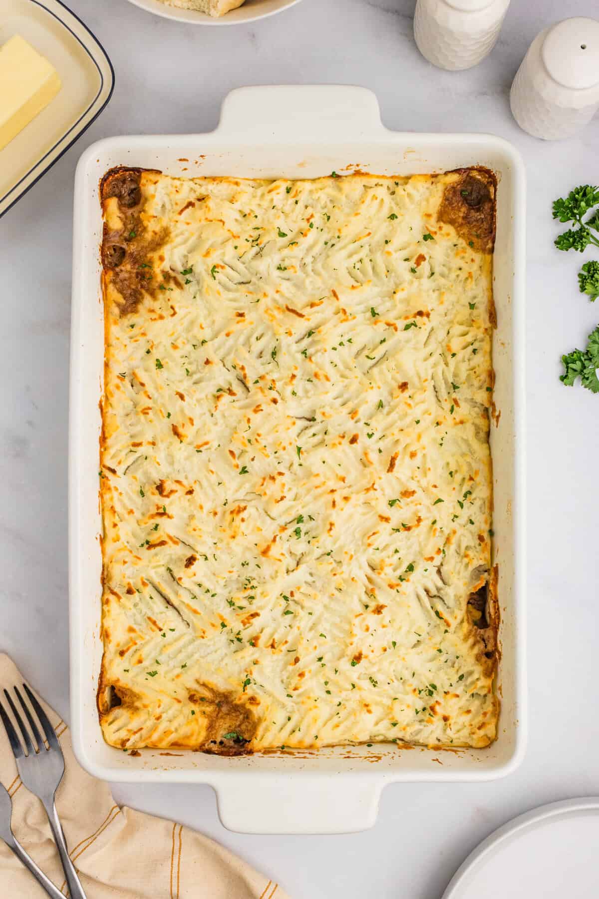 A baked cottage pie in a white casserole dish with a golden-brown mashed potato topping.