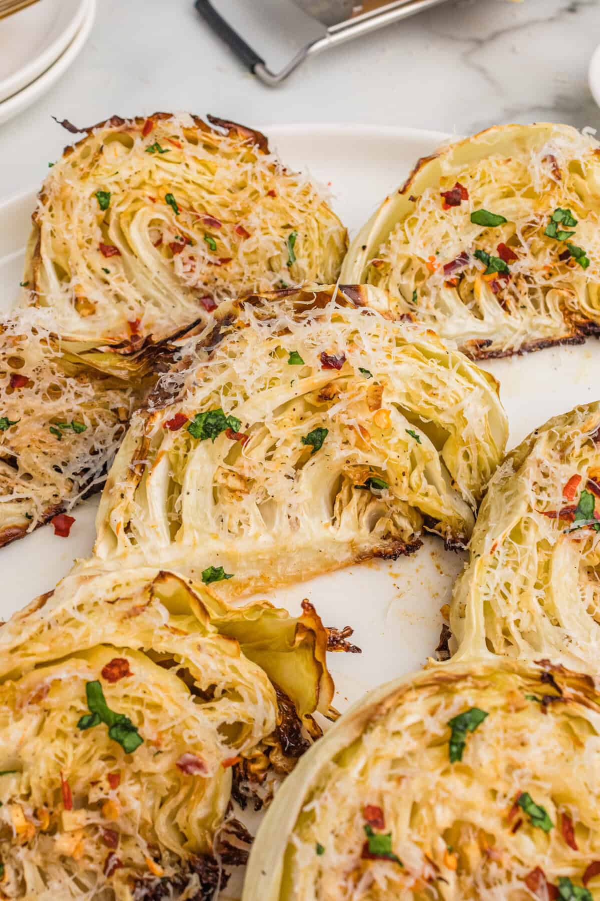 Overhead view of roasted cabbage wedges with garlic, parmesan cheese, and red pepper flakes.