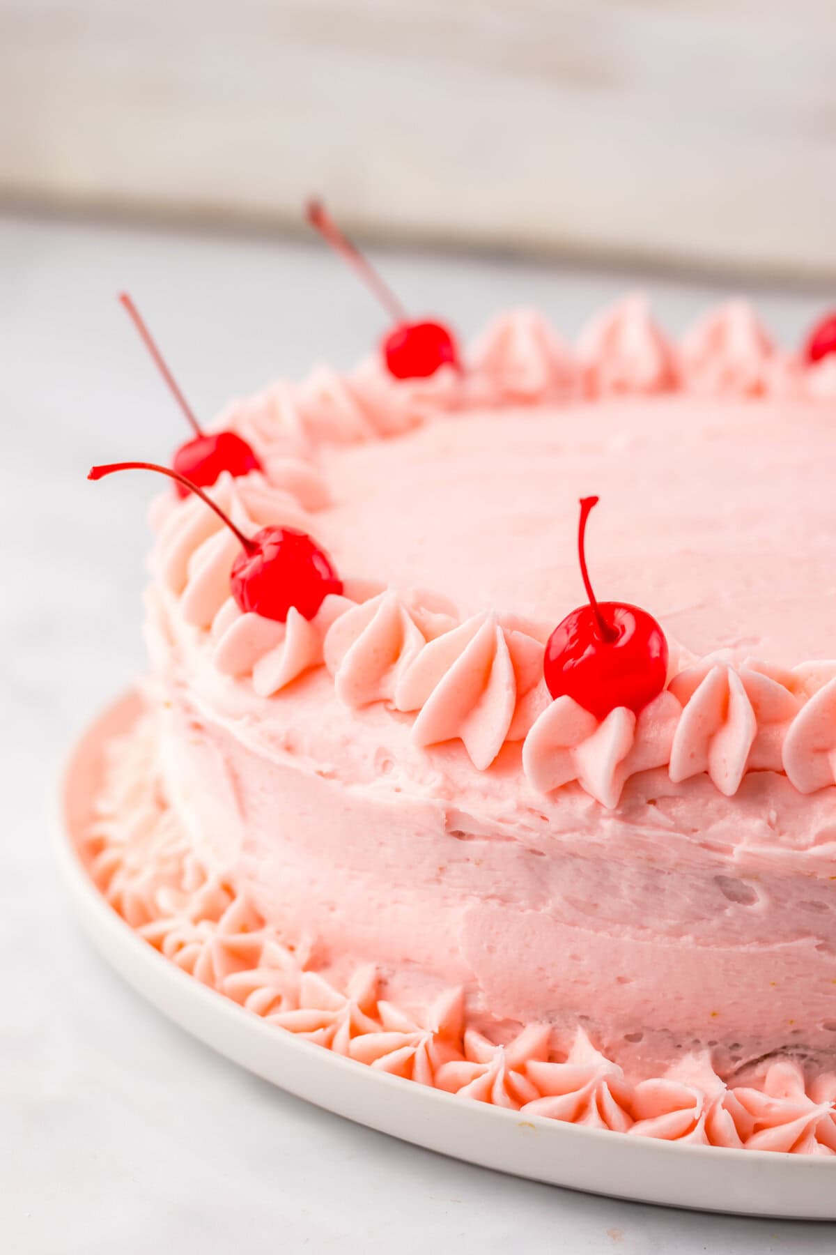 Maraschino cherry cake with piped pink frosting and cherries on top.