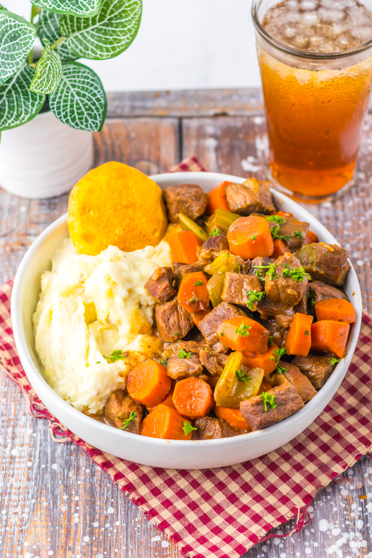 Bowl of slow cooker cracker barrel copycat pot roast with carrots, celery, mashed potatoes, and a biscuit.