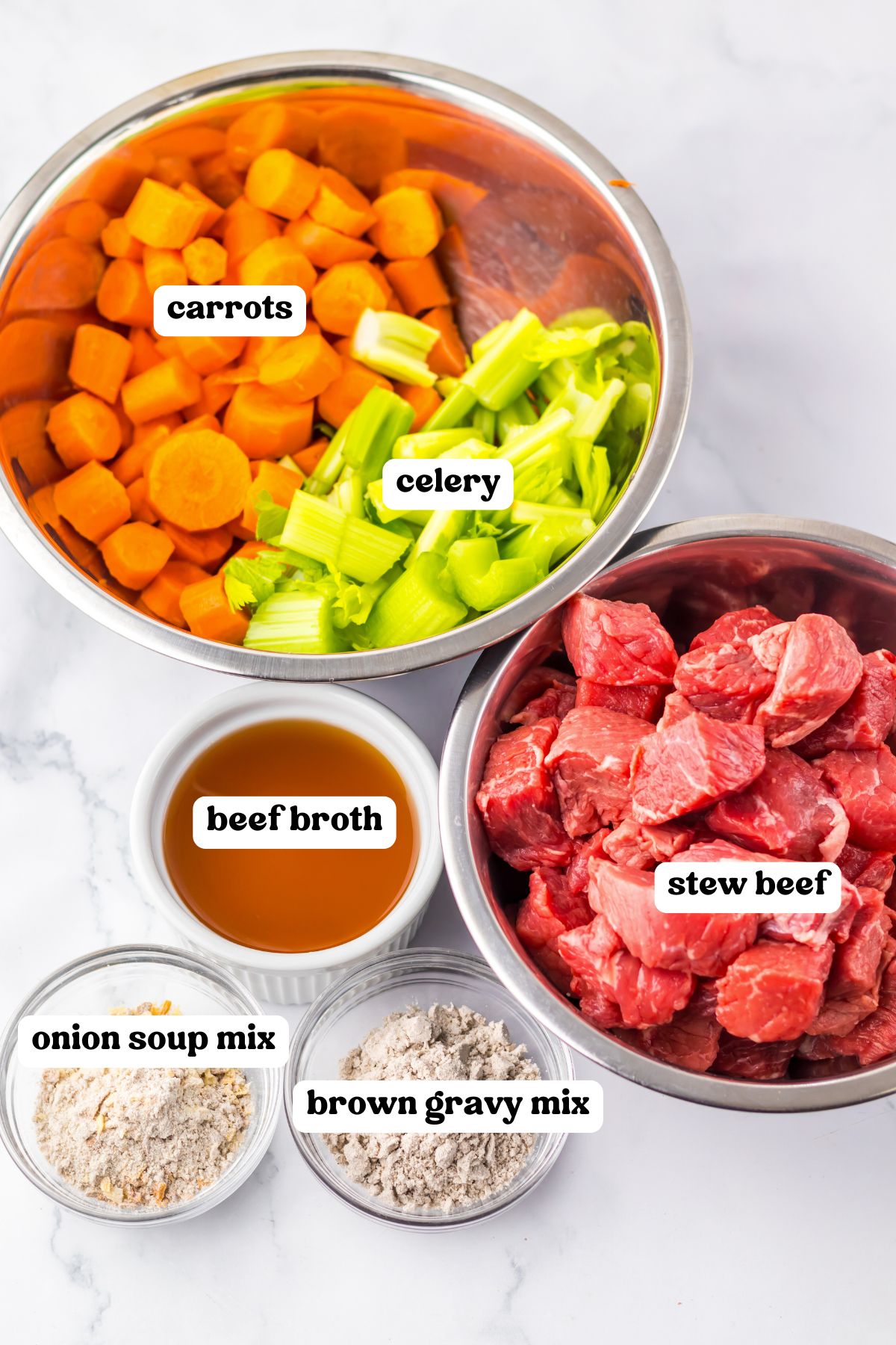 Labeled ingredients in bowls: sliced carrots and chopped celery, raw cubed stew beef, beef broth, onion soup mix, and brown gravy mix.