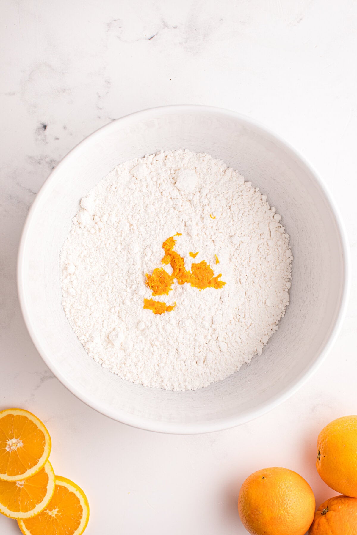 Bowl of dry ingredients with orange zest on top.