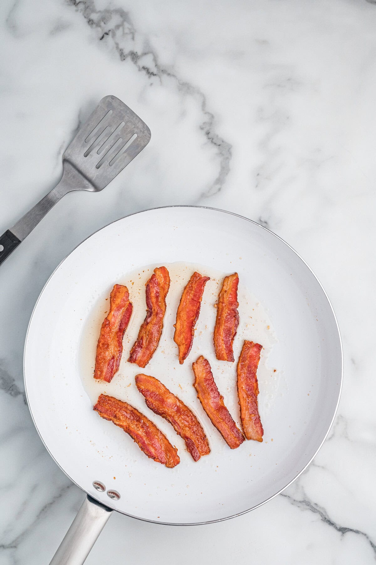 Skillet with cooked bacon strips.
