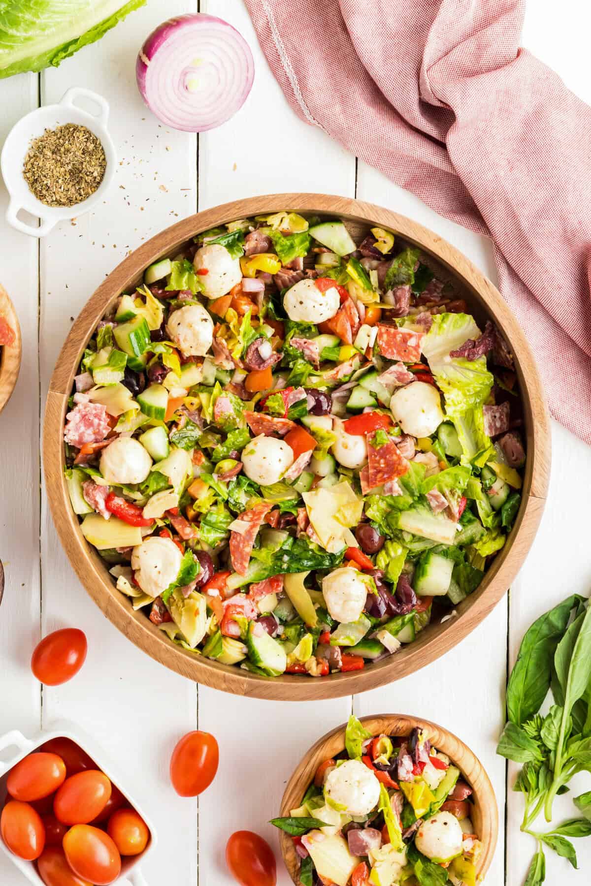  Flat lay of antipasto salad in a large and small bowl with fresh ingredients.