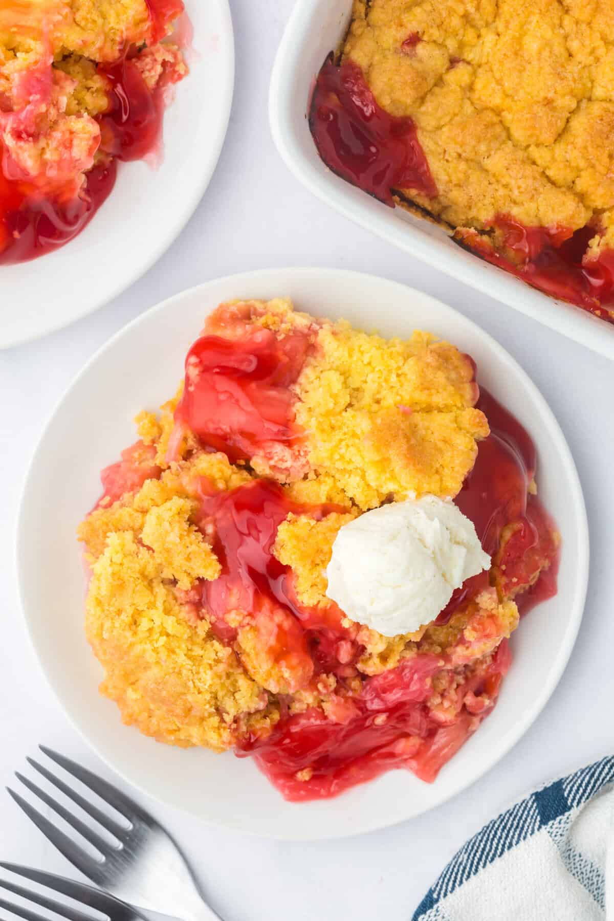 A plated serving of rhubarb dump cake topped with a scoop of vanilla ice cream.