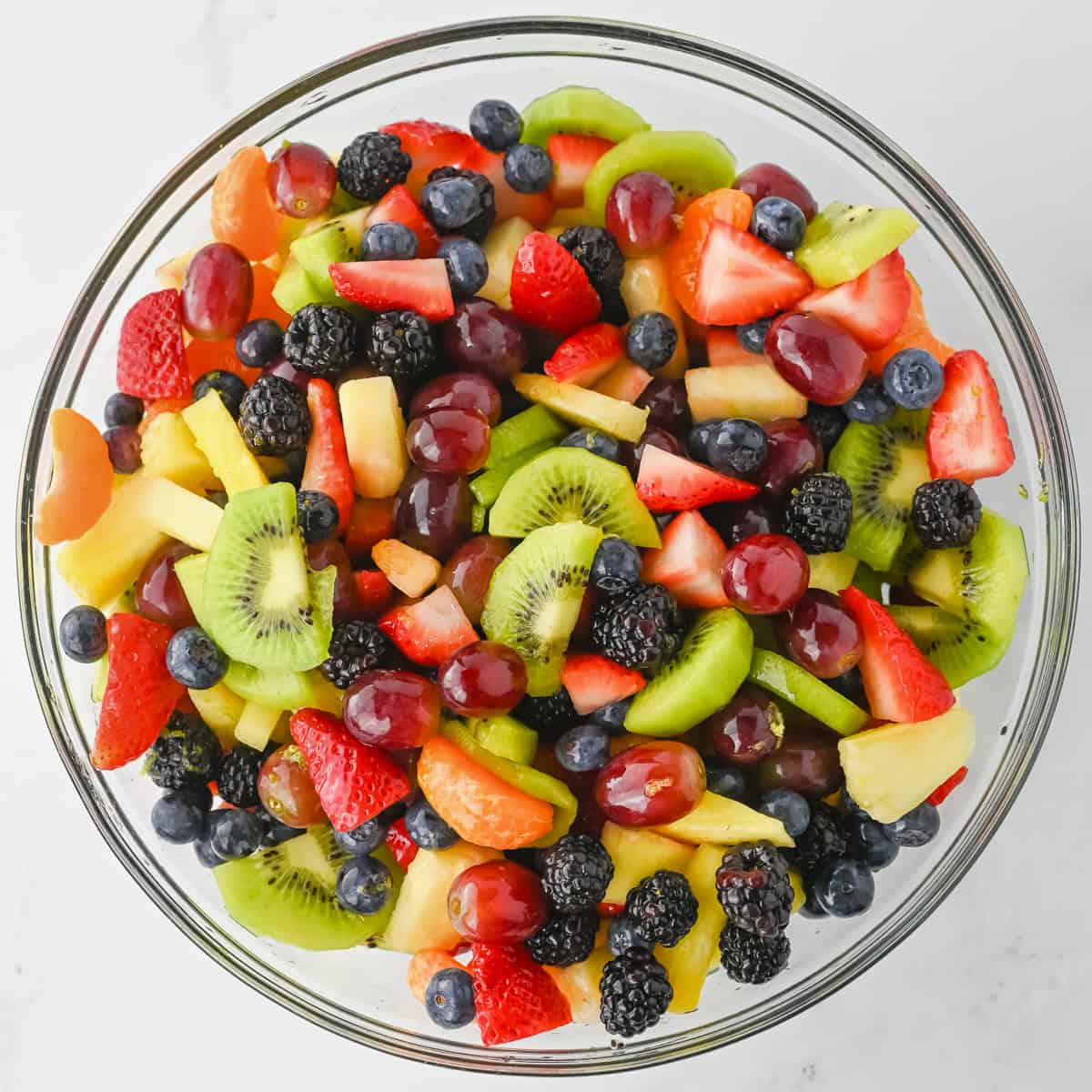 Rainbow fruit salad in a large glass bowl.