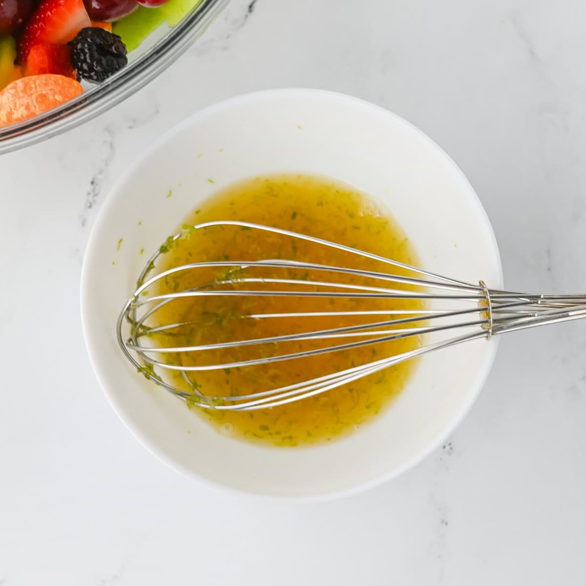 Honey lime dressing in a bowl with a whisk.
