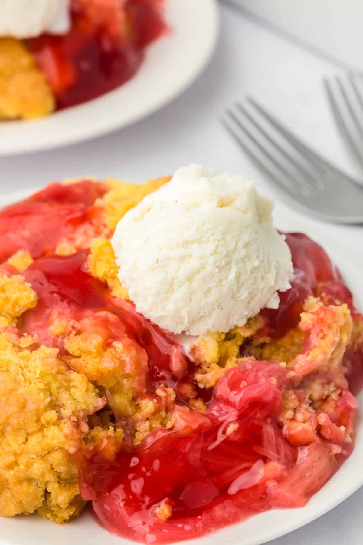 R
Rhubarb dump cake on a plate, topped with a round scoop of vanilla ice cream. The golden cake crumbles blend with the vibrant red filling beneath.