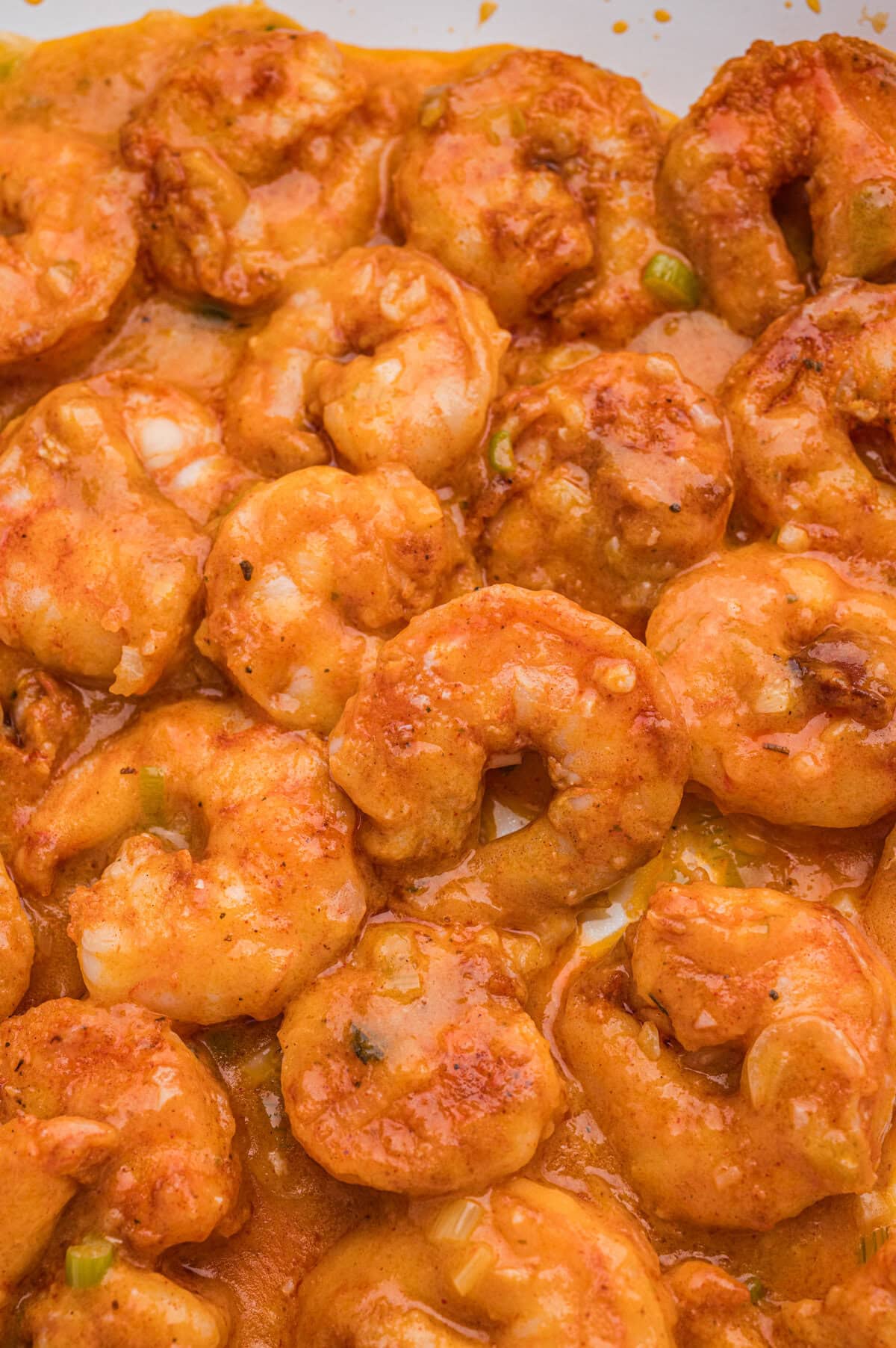 Close-up of cooked seasoned shrimp coated in a creamy orange sauce.