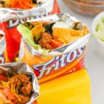Fritos walking tacos with toppings like shredded cheese, beans, sour cream, and lettuce.