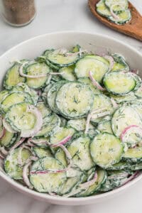 Bowl of creamy cucumber dill salad, made with sliced cucumbers, red onion, and fresh dill in a creamy dressing