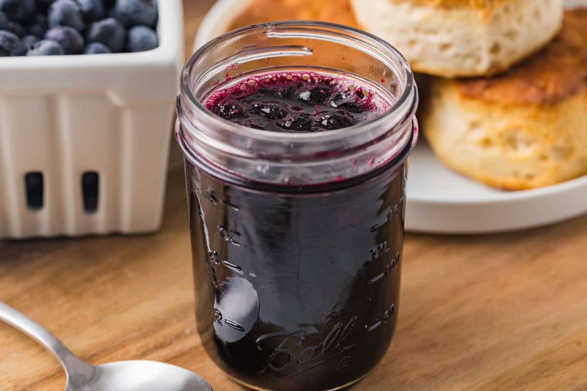 3-Ingredient blueberry jam next to biscuits and fresh blueberries.