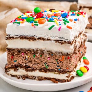 Slice of ice cream sandwich cake with sprinkles and M&Ms on top.