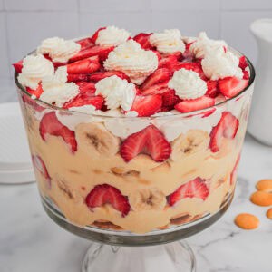 Strawberry banana pudding layered with fruit, pudding, and whipped cream in a trifle dish.