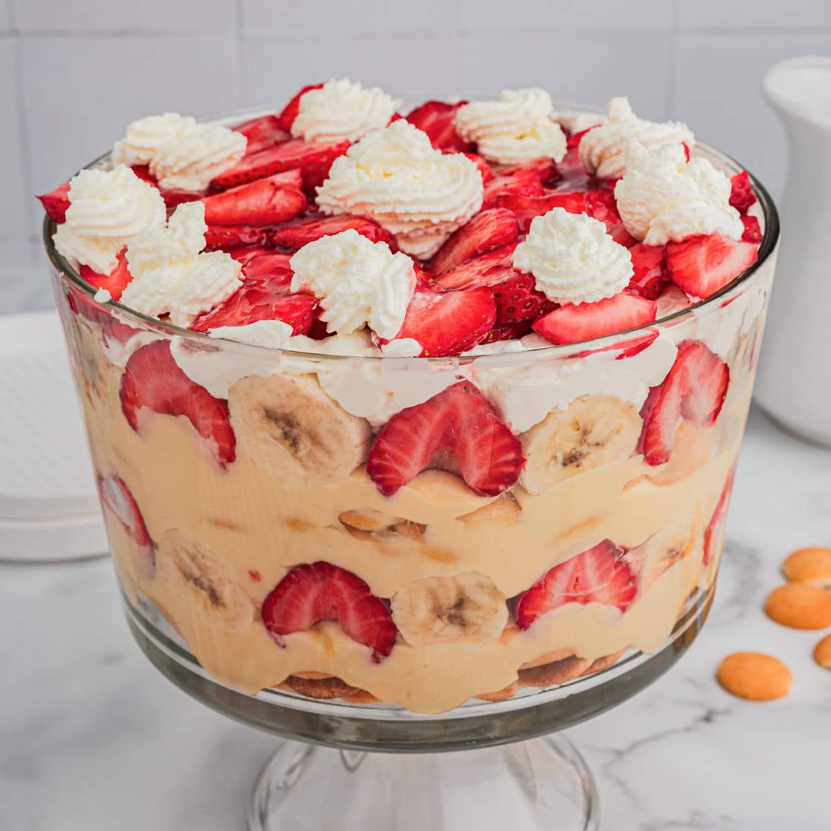 Strawberry banana pudding layered with fruit, pudding, and whipped cream in a trifle dish.