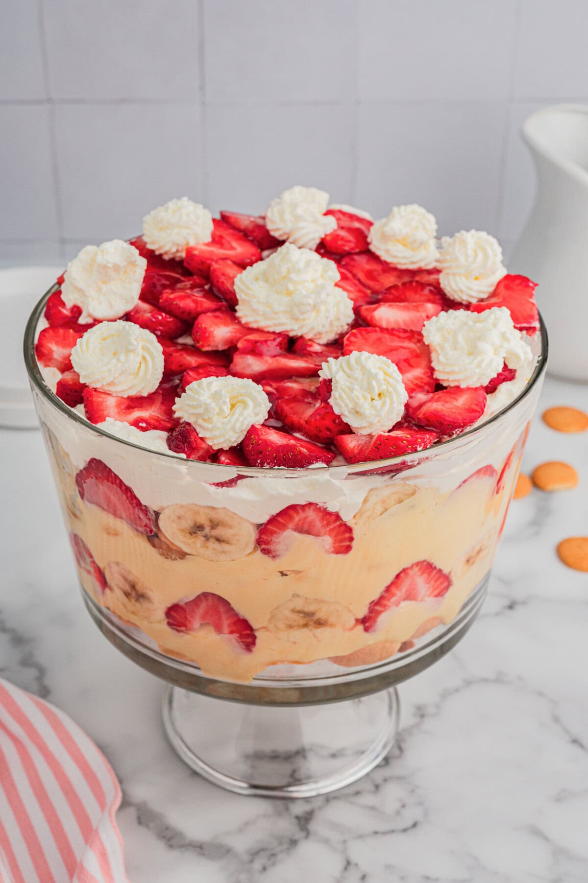 Strawberry banana pudding layered with fruit, pudding, and whipped cream in a trifle dish.