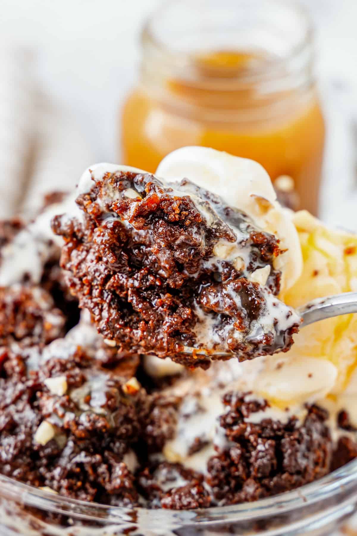 Spoon holding a bite of chocolate dump cake and ice cream.