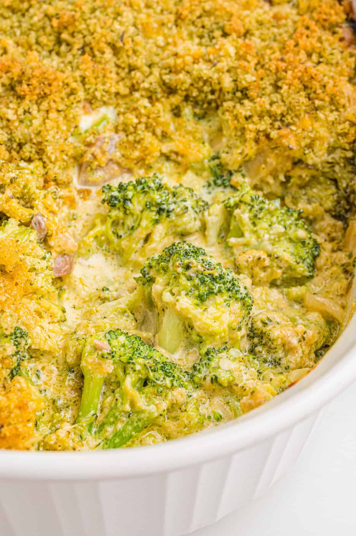 Broccoli casserole in a white dish, showing broccoli florets coated in creamy sauce and melted cheddar cheese with a golden breadcrumb topping.