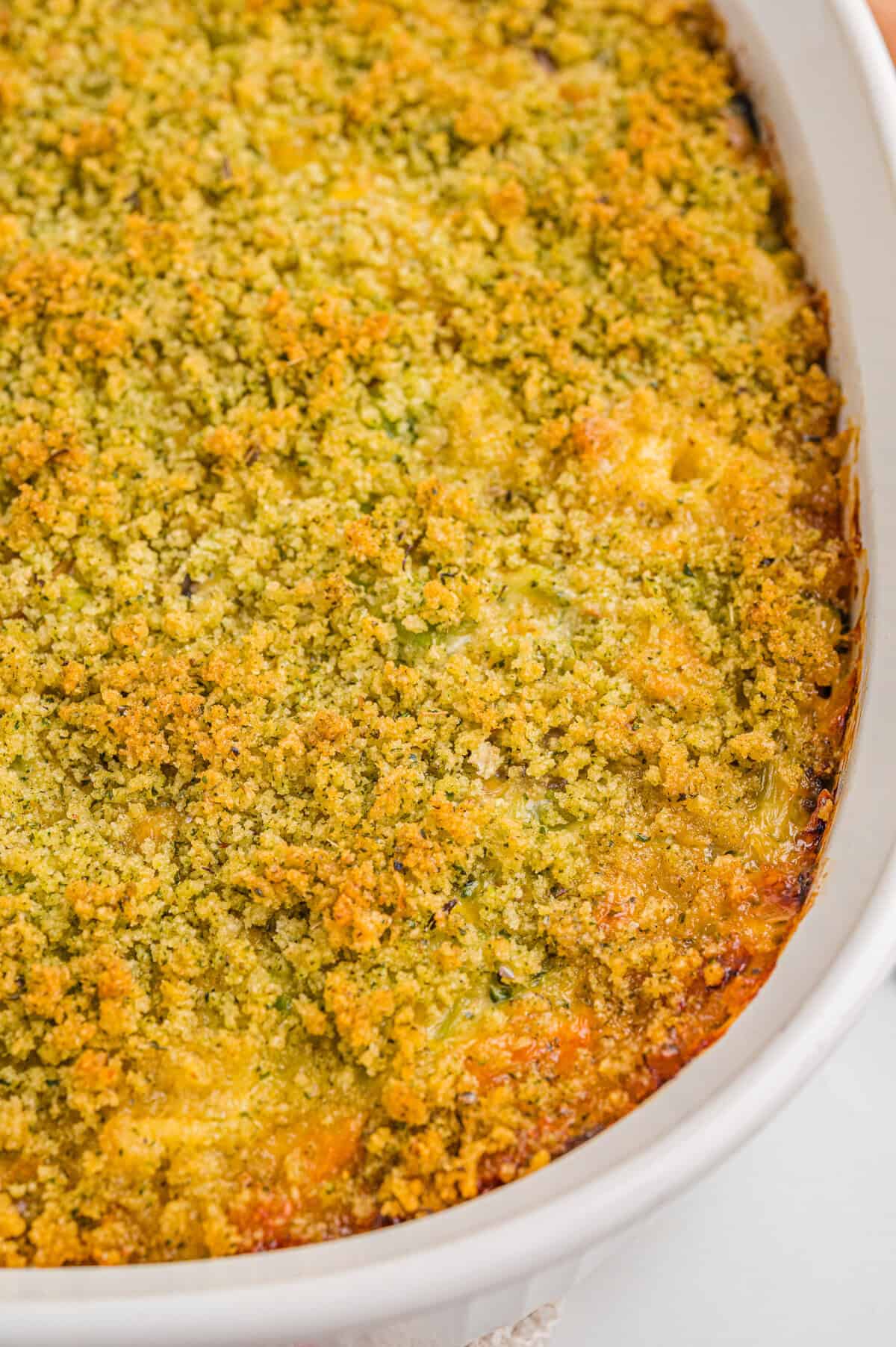 Overhead view of a freshly baked broccoli cheddar casserole in a white dish, with a uniformly browned breadcrumb and cheese topping.