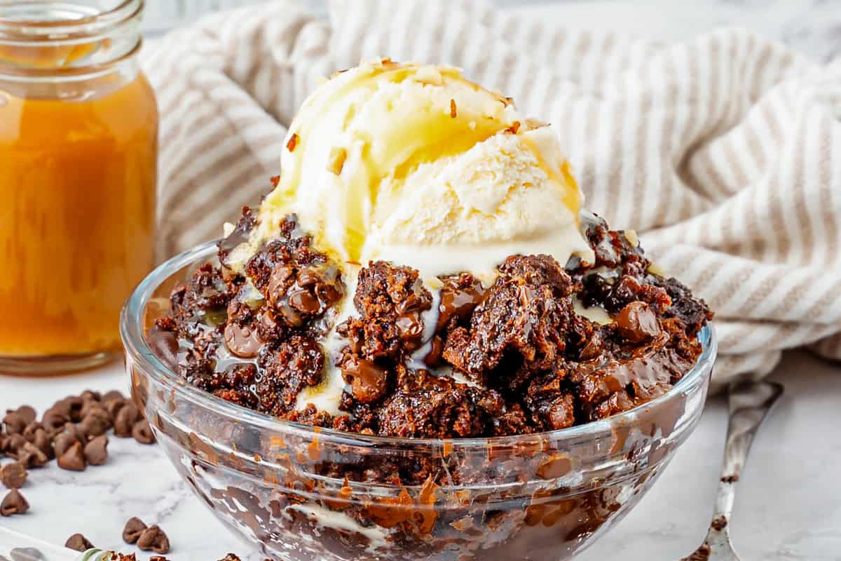 Chocolate dump cake topped with vanilla ice cream and caramel sauce.