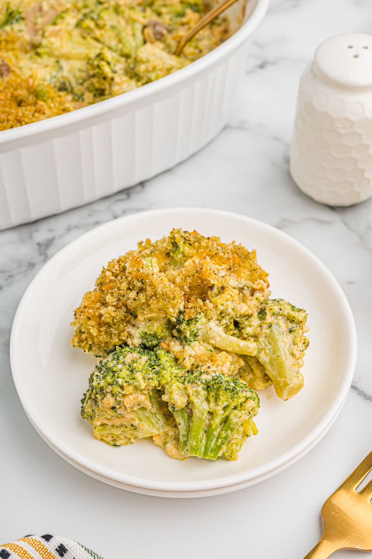 Serving of broccoli cheese casserole on a white plate.