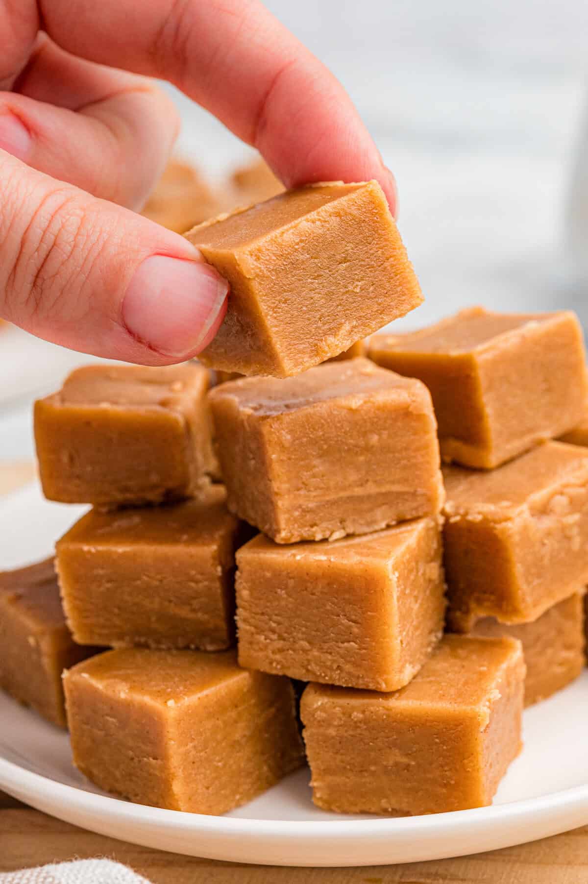 Hand picking up a square of peanut butter fudge.