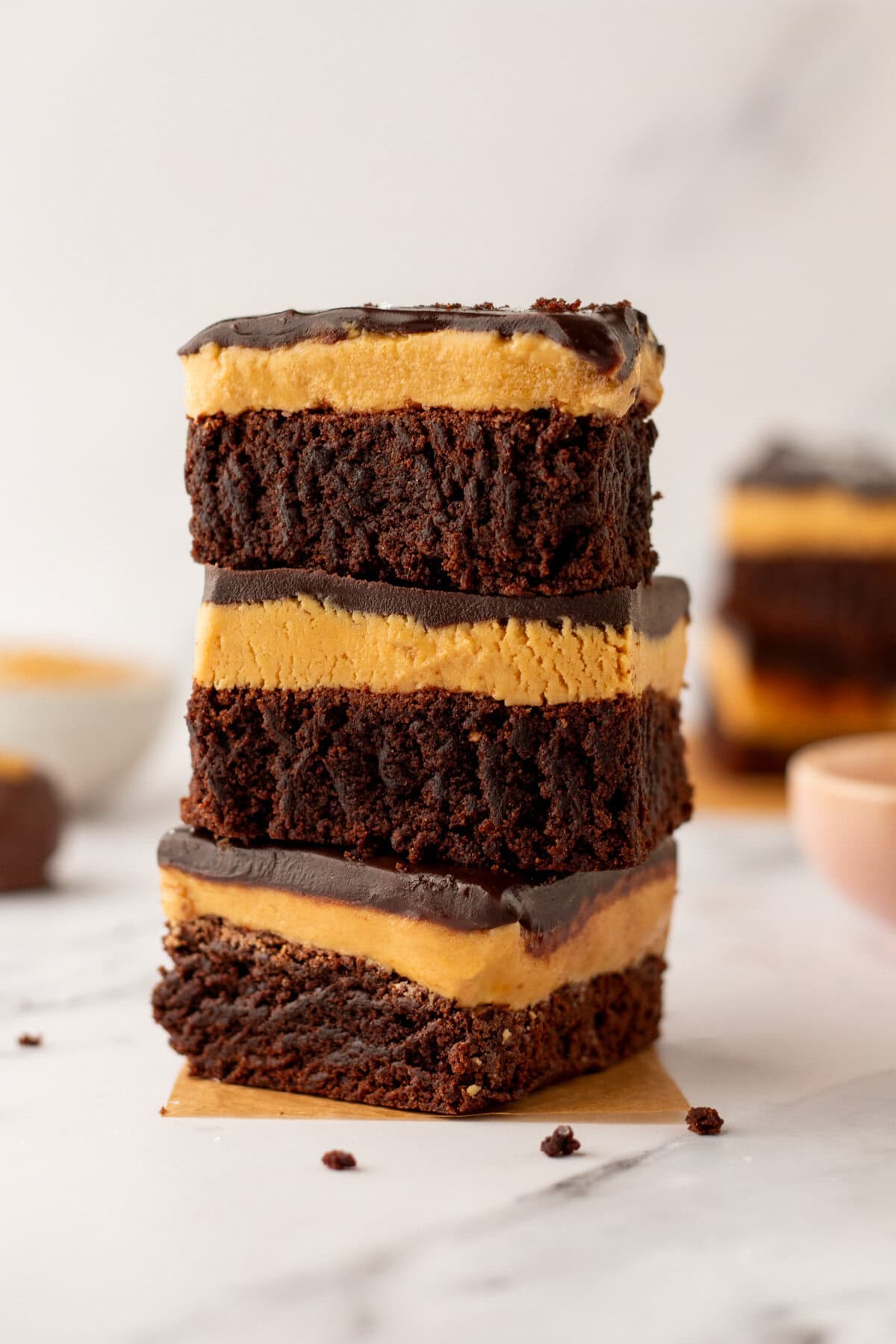 Stack of three peanut butter chocolate buckeye brownies on parchment paper.
