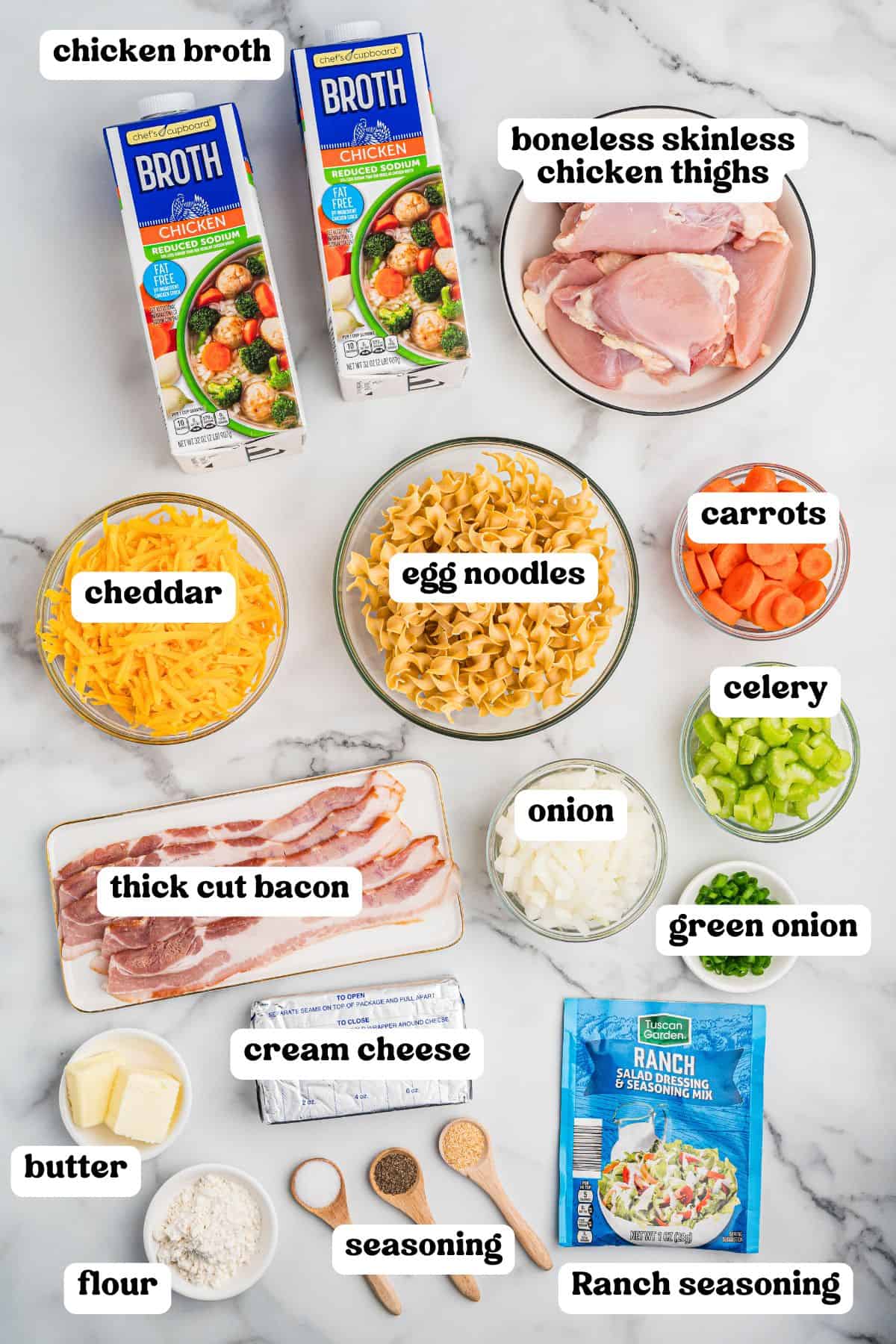 Crack chicken noodle soup ingredients including chicken broth, boneless skinless chicken thighs, egg noodles, cheddar, carrots, celery, green onion, thick cut bacon, onion, butter, flour, cream cheese, various seasonings, and a packet of Ranch seasoning.