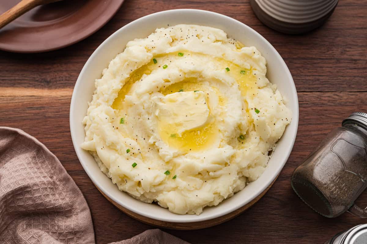Bowl of old fashioned mashed potatoes topped with a pat of butter.