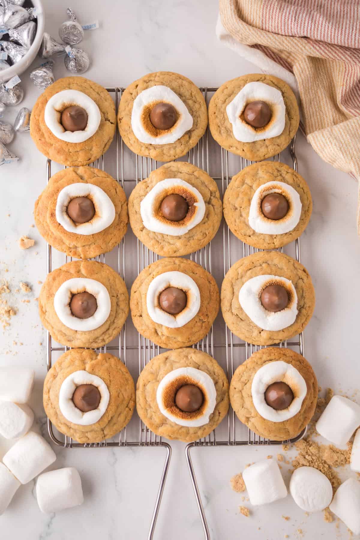 Overhead view of s'mores cookies topped with marshmallows and hershey kisses on wire cooling rack.