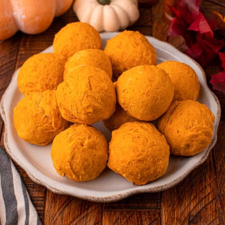 Place of 2 ingredient pumpkin dinner rolls with fall decorate in background.