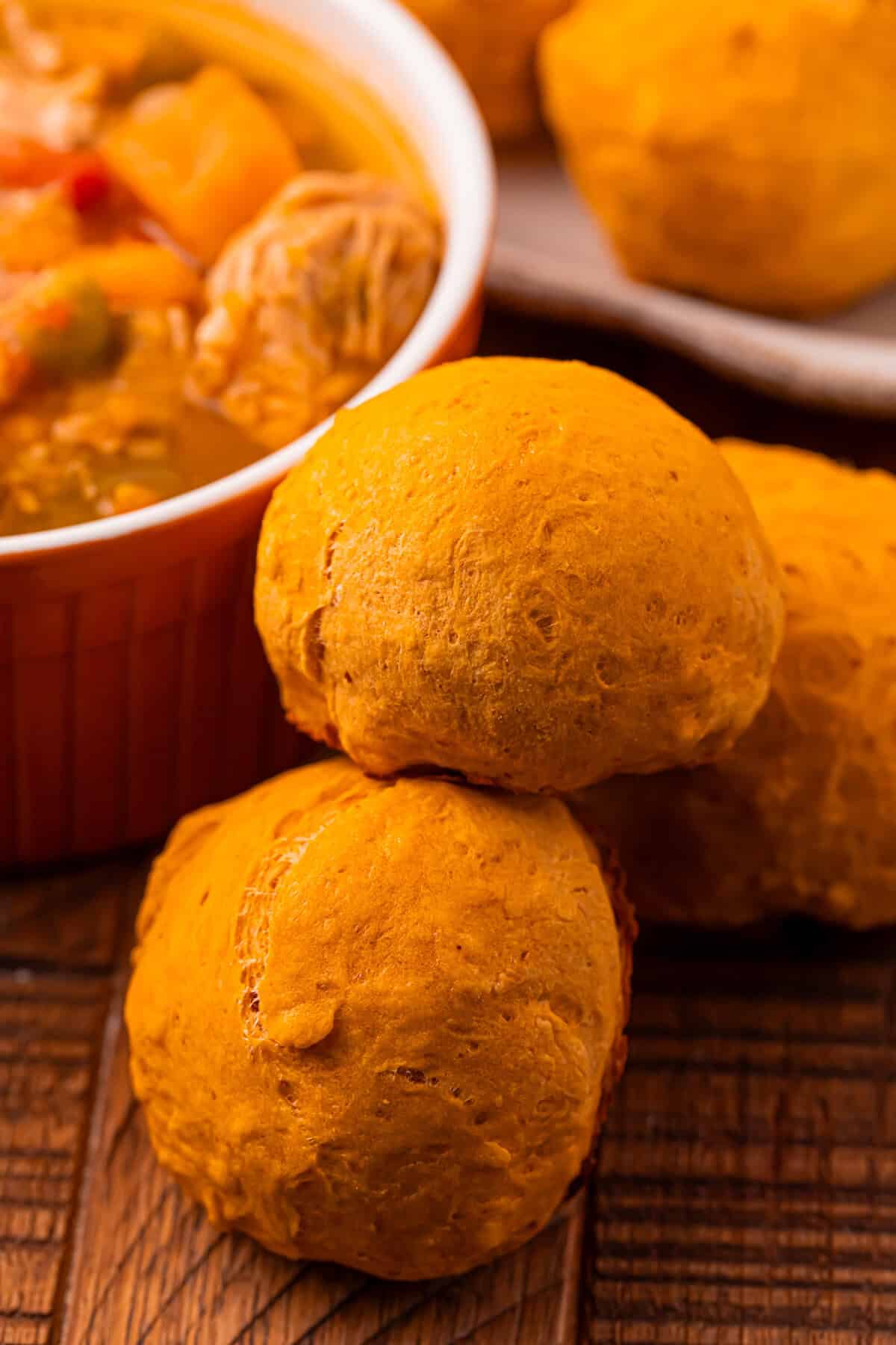 Pumpkin dinner rolls served with a bowl of soup.
