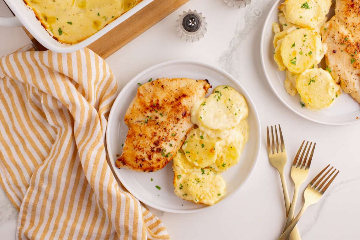 Plated scalloped potatoes with baked chicken breast.