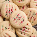 Whipped shortbread cookies with fork marks and is topped with red, green, and white nonpareil sprinkles.