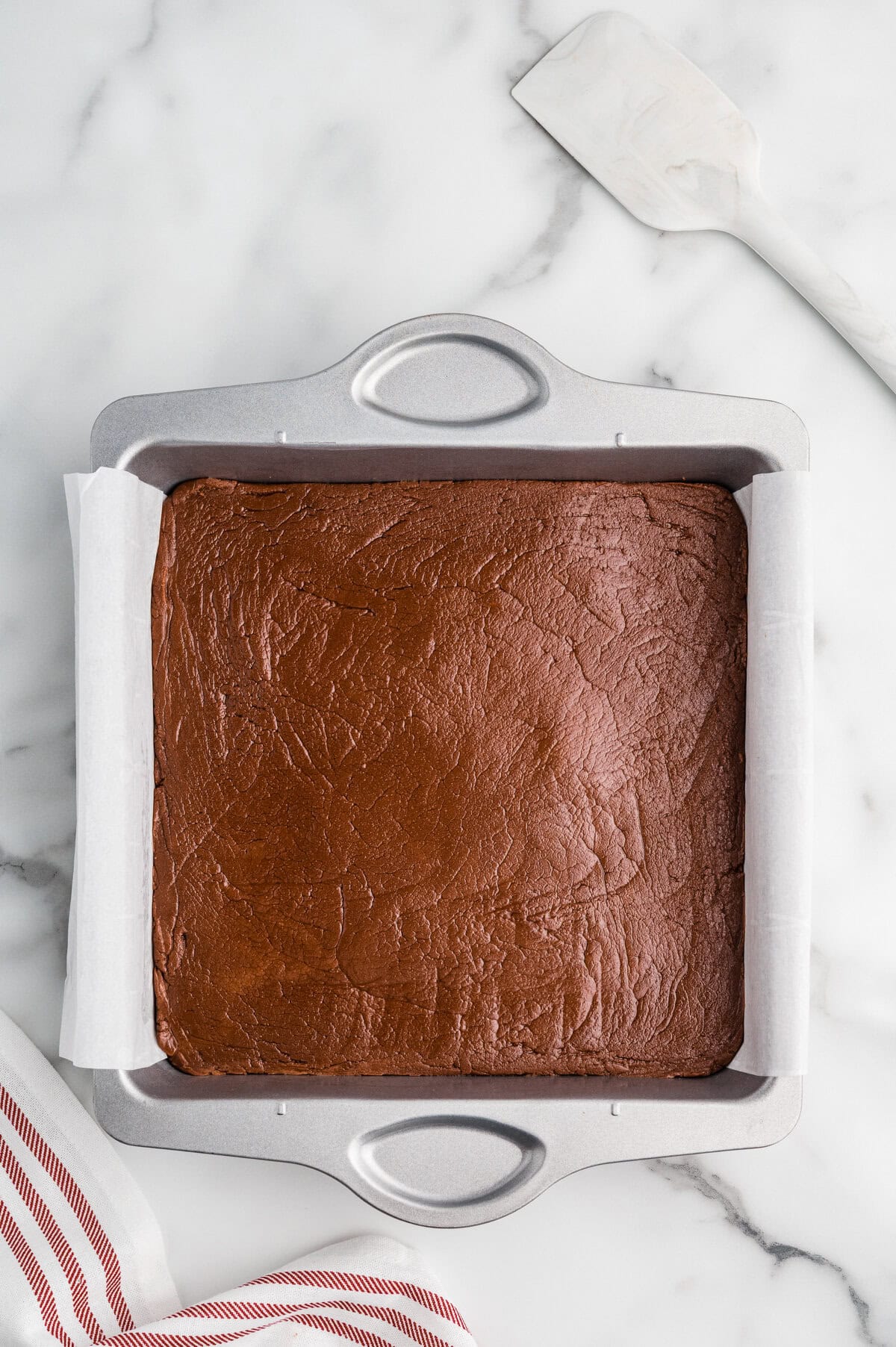Chocolate fudge in a square parchment-lined pan.
