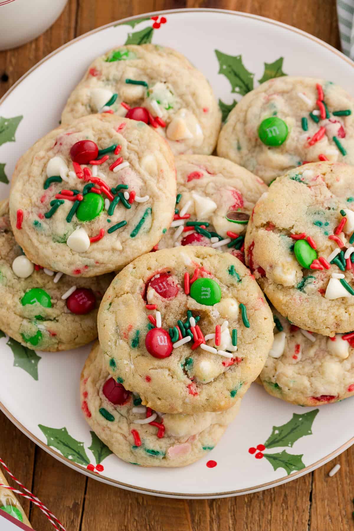 A plate of festive Christmas cookies with red and green M&Ms, white chocolate chips, and red, green, and white sprinkles. 
