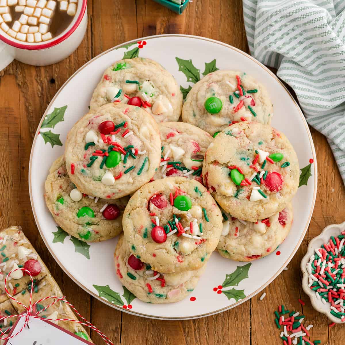 Overhead view of Christmas M&M cookies with white chocolate chips and sprinkles on a holiday plate.