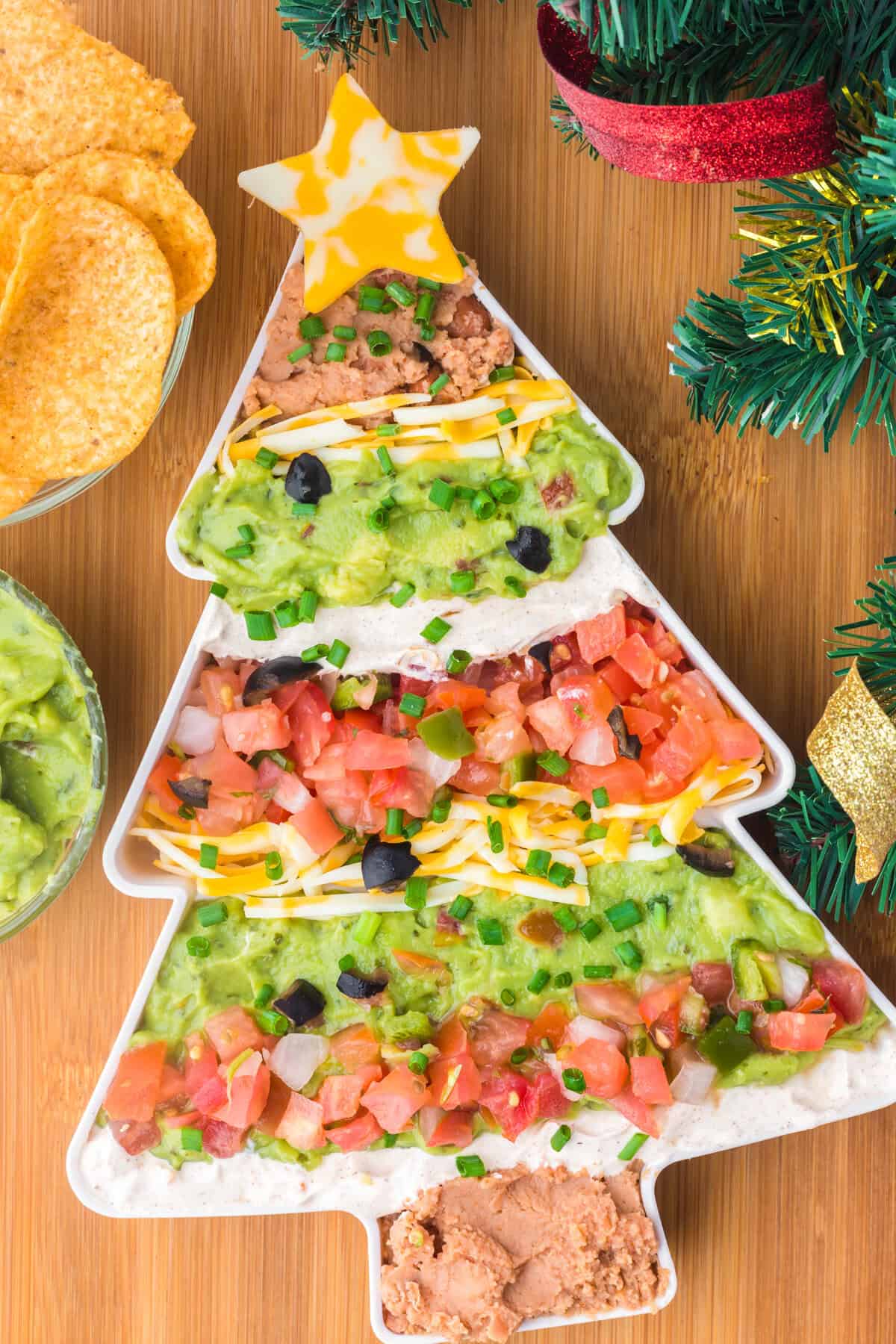 Christmas taco dip with decorations and tortilla chips.