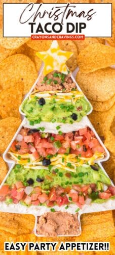 A Christmas tree-shaped taco dip surrounded by tortilla chips. Layers include beans, sour cream, guacamole, pico de gallo, cheese, chives, and olives, topped with a marbled cheese star. Text reads “Christmas Taco Dip” and “Easy Party Appetizer!!” with the URL crayonsandcravings.com.