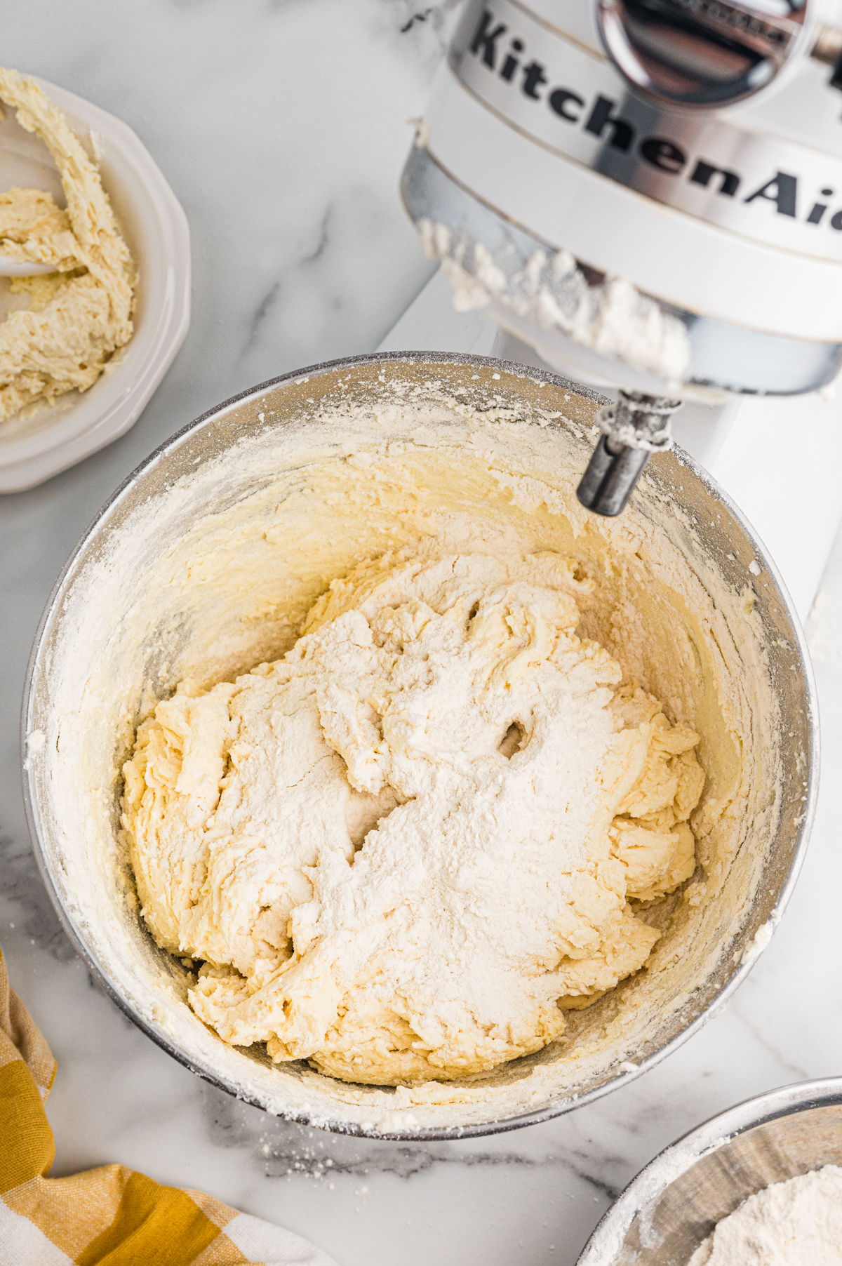 Flour added to thick batter in stand mixer bowl.