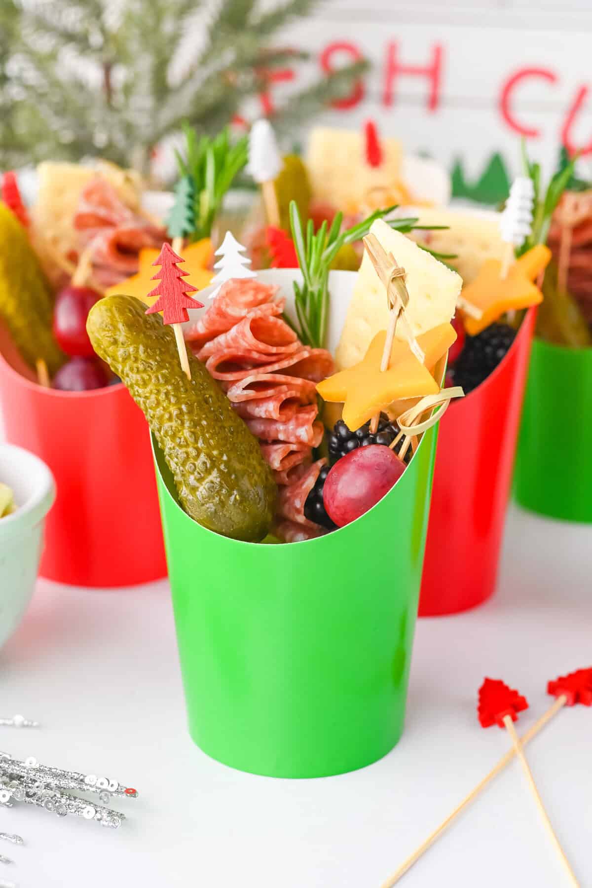 Green charcuterie cup with holiday picks and snacks.