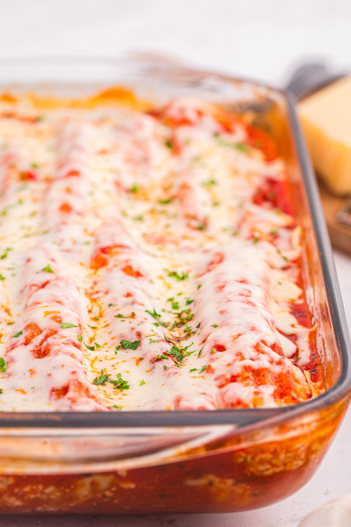 Close-up of cheesy baked manicotti in a glass dish.