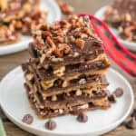 Stacked pieces of saltine cracker toffee with pecans on top.