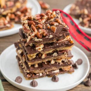 Stacked pieces of saltine cracker toffee with pecans on top.