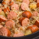 Kielbasa with sauerkraut, caraway seeds, and apple chunks in a crock pot.